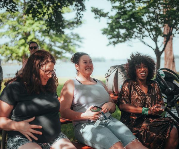 Group of pregnant women sitting together on yoga mats and smiling.